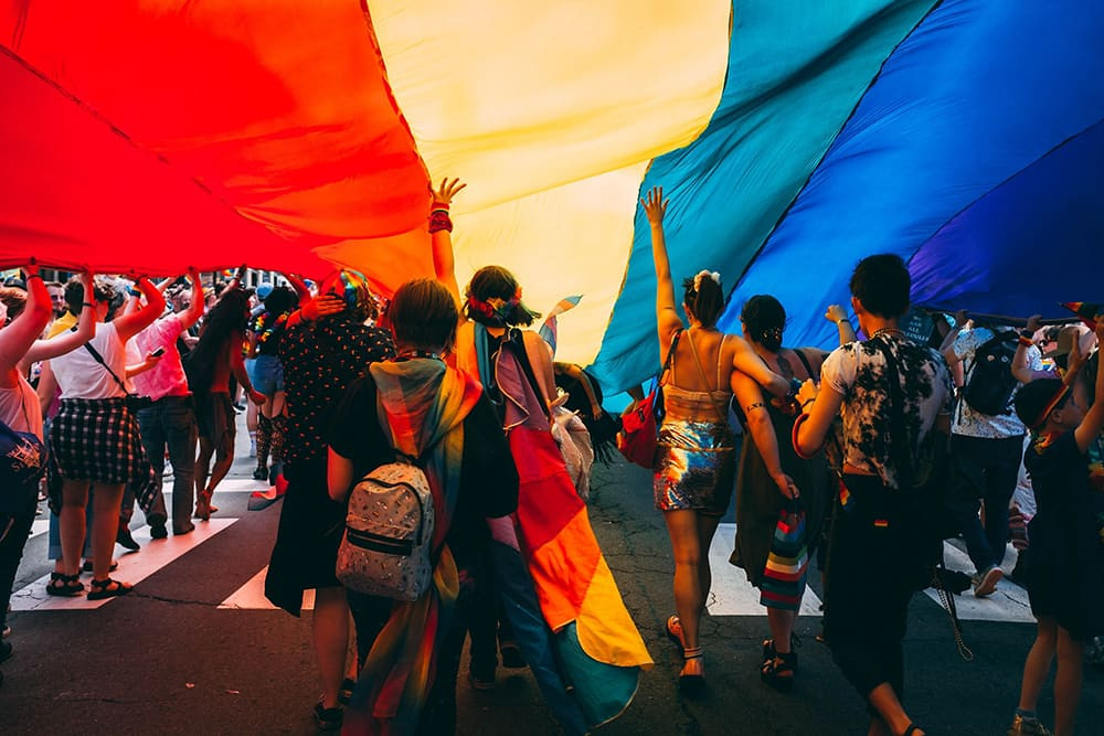 Image of Pride march under big rainbow flag