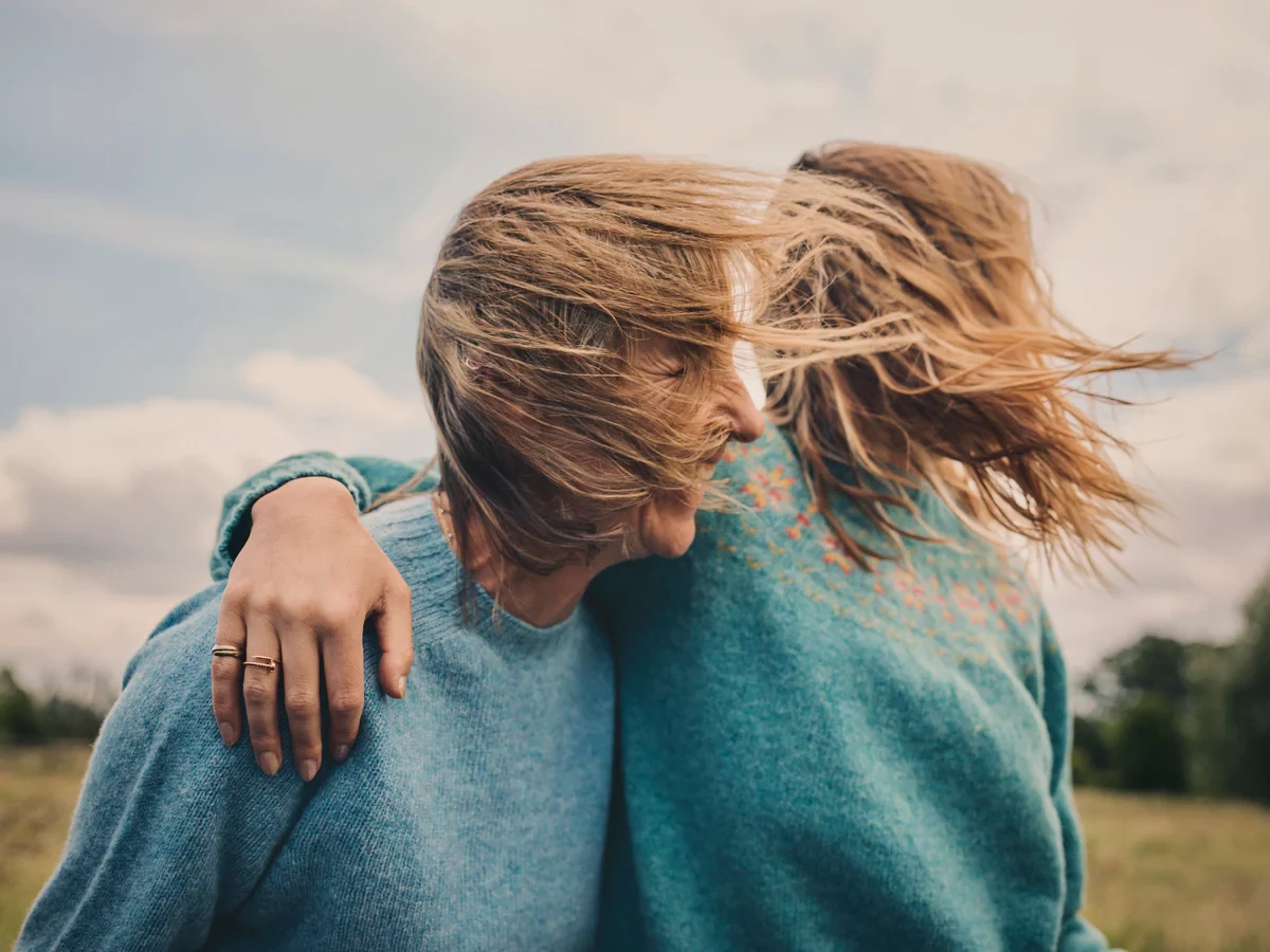 Two woman hugging in the wind wearing Gladstone / Hellen jumpers